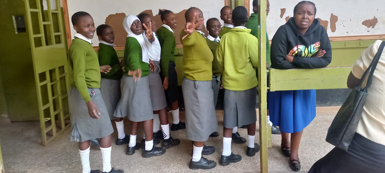 Students gathered around Period Pride Kenya educator during classroom menstrual health education session